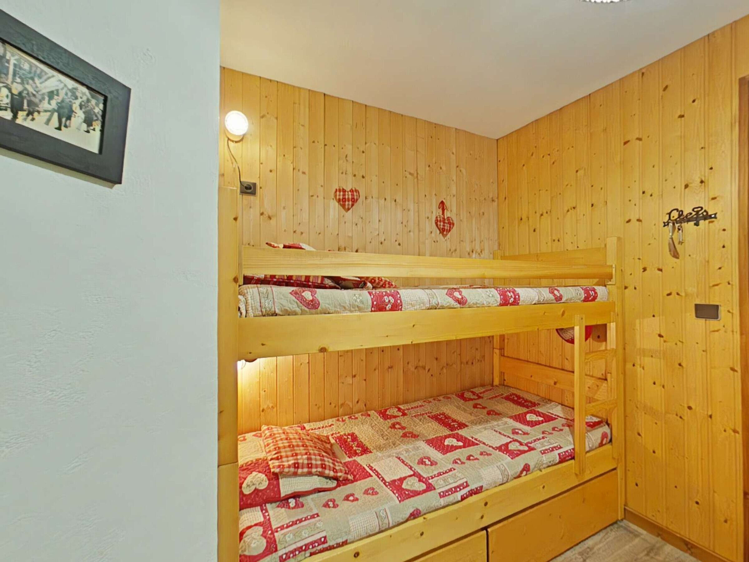 A bunk bed room with wooden walls, a framed picture, and a small light fixture.