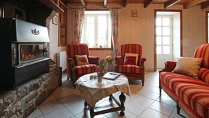 Een gezellige woonkamer met een open haard, twee fauteuils, een bank en een tafel met een bloevas.