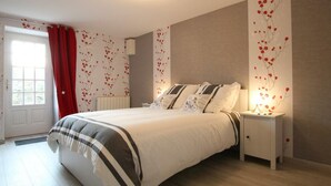 Een slaapkamer met een bed, nachtkastjes, een radiator en een raam met rode gordijnen.
