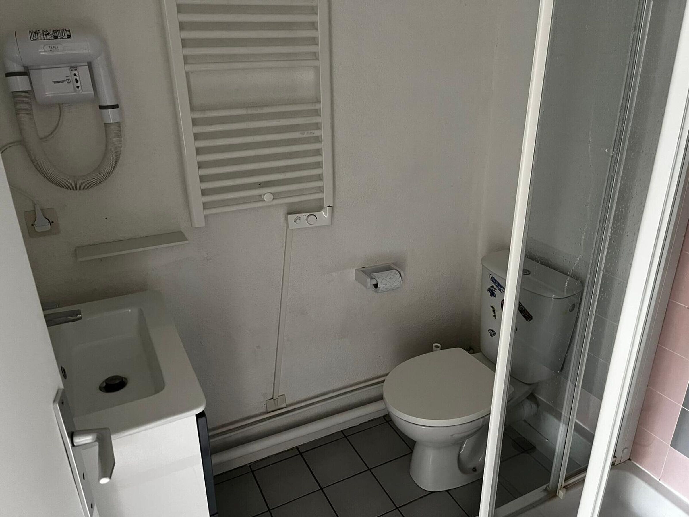 A compact bathroom with a toilet, a sink, and a shower.