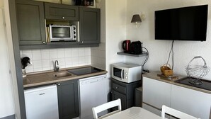 Cocina compacta con lavavajillas, microondas y cafetera sobre la encimera.