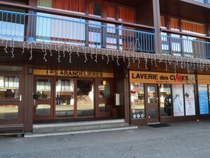 Um edifício com duas vitrines, uma com a inscrição "LES ARANDELIERES" e outra com "LAVERIE des CAMES".