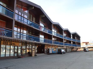 A multi-story building with balconies, a shop on the ground floor, and a parking area. - 2-room apartment in the heart of Arc 1800 - 4 guests (Les Arcs 1800)