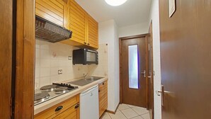 Una cucina compatta con mobili in legno, un forno a microonde, un lavello e una lavastoviglie.