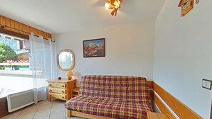 Una stanza accogliente con un divano a quadri, un comò in legno, uno specchio rotondo e un quadro appeso al muro.