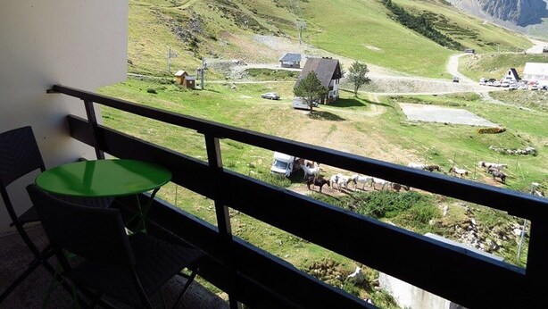 A balcony with a view of a mountainous landscape, including a small village and grazing animals. - Studio cabin for 4, covered parking, 50m from slopes (La Mongie)