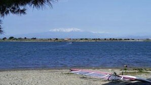 A beach with a clear view of the sea and a distant mountain range.