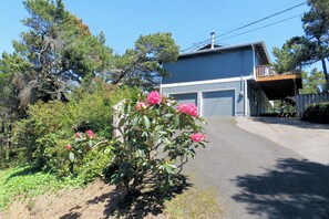 A residential property with a garage, a covered driveway, and a garden with flowering plants.