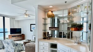 A modern living room with a large window, a flat-screen TV, a sofa, and a ceiling fan.