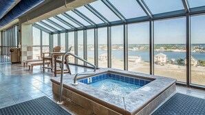 A large indoor swimming pool with a view of a beach and buildings.