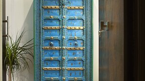A blue cabinet with metal studs and a decorative top, placed against a wall with a wooden floor. - Welcome to Tabata apartment in the hearth of Florence (Firenze)