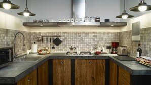 A modern kitchen with a central island, wooden cabinets, and a tiled backsplash. - Welcome to Tabata apartment in the hearth of Florence (Firenze)