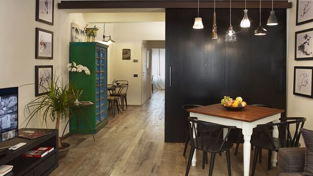 A dining area with a wooden table and chairs, a green cabinet, and a television on a stand. - Welcome to Tabata apartment in the hearth of Florence (Firenze)