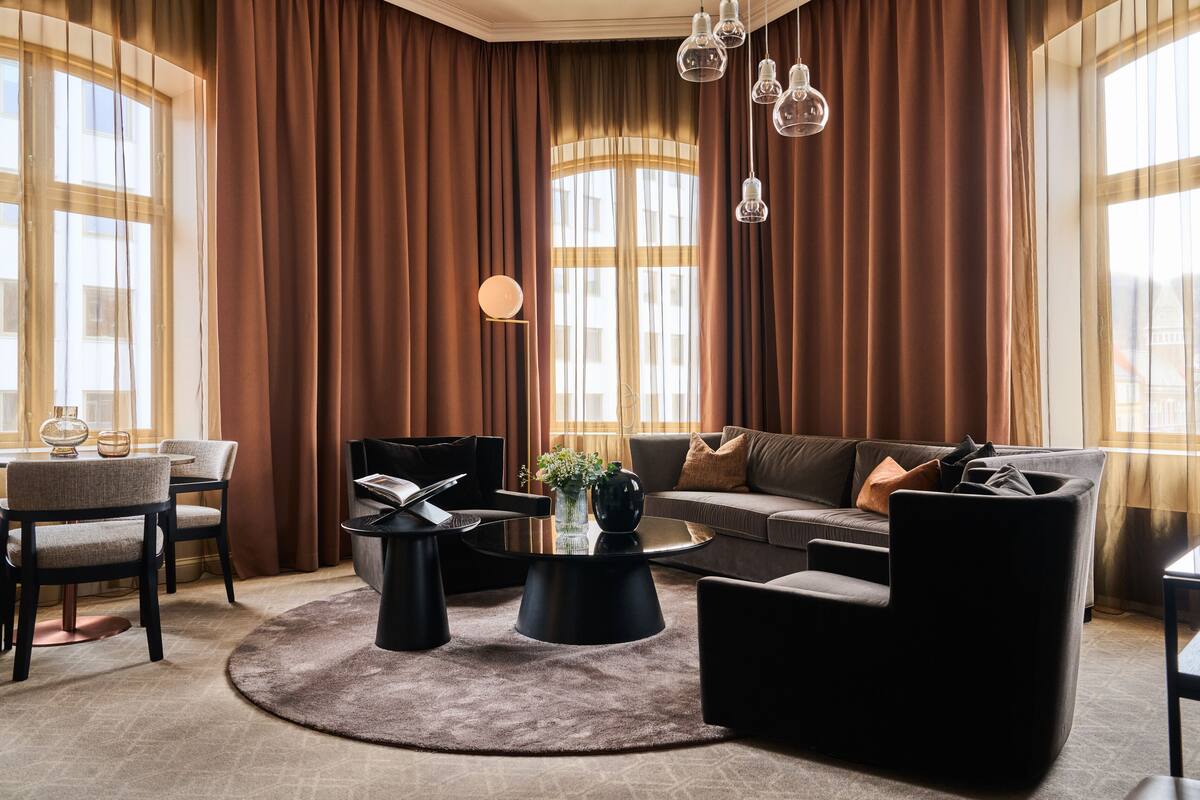 A modern living room with a sofa, chairs, a coffee table, and a dining area.
