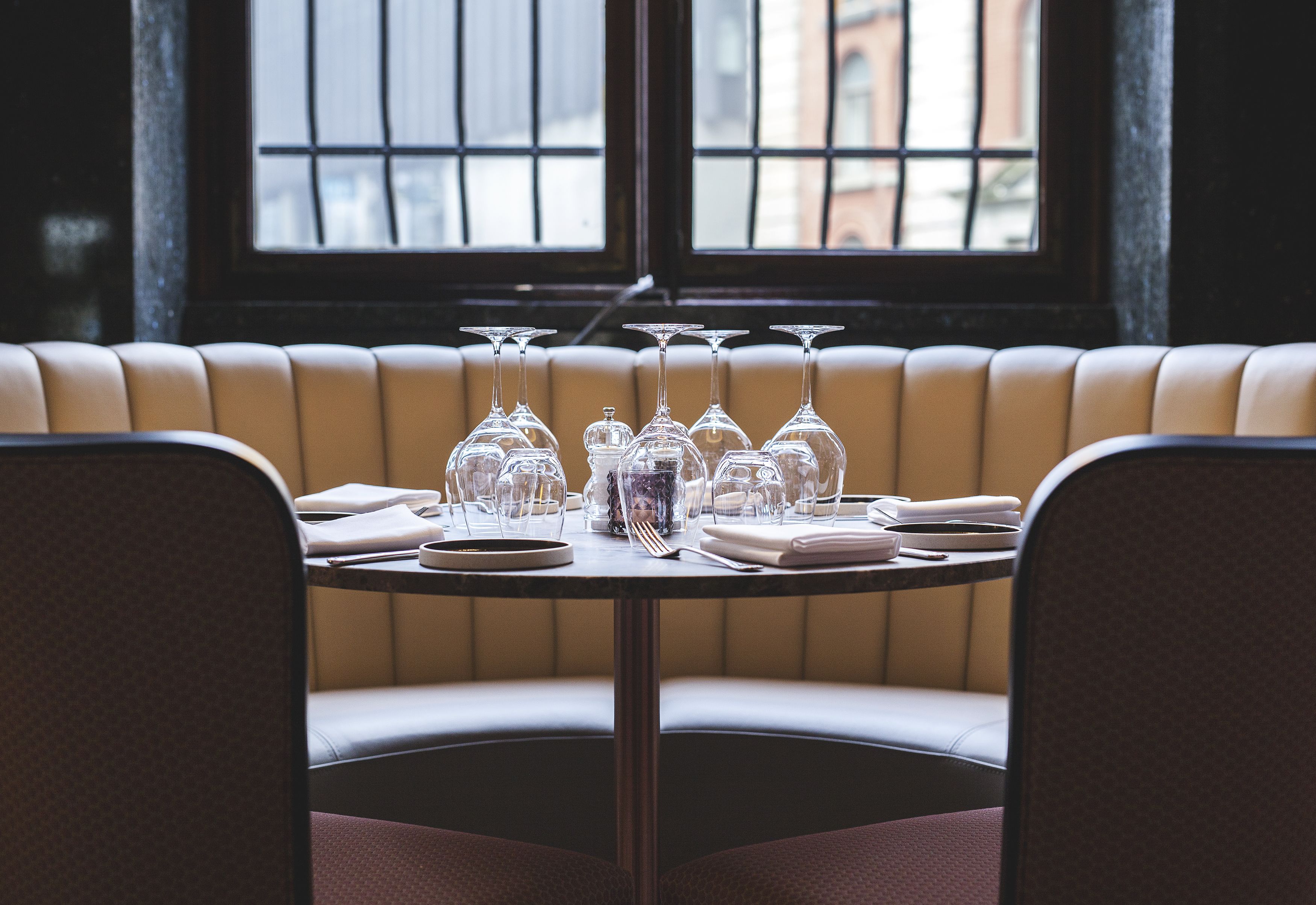A restaurant booth with a table set for a meal, including wine glasses and cutlery.
