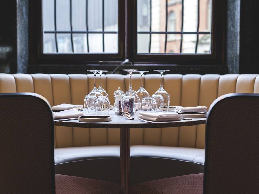 A restaurant booth with a table set for a meal, including wine glasses and cutlery.