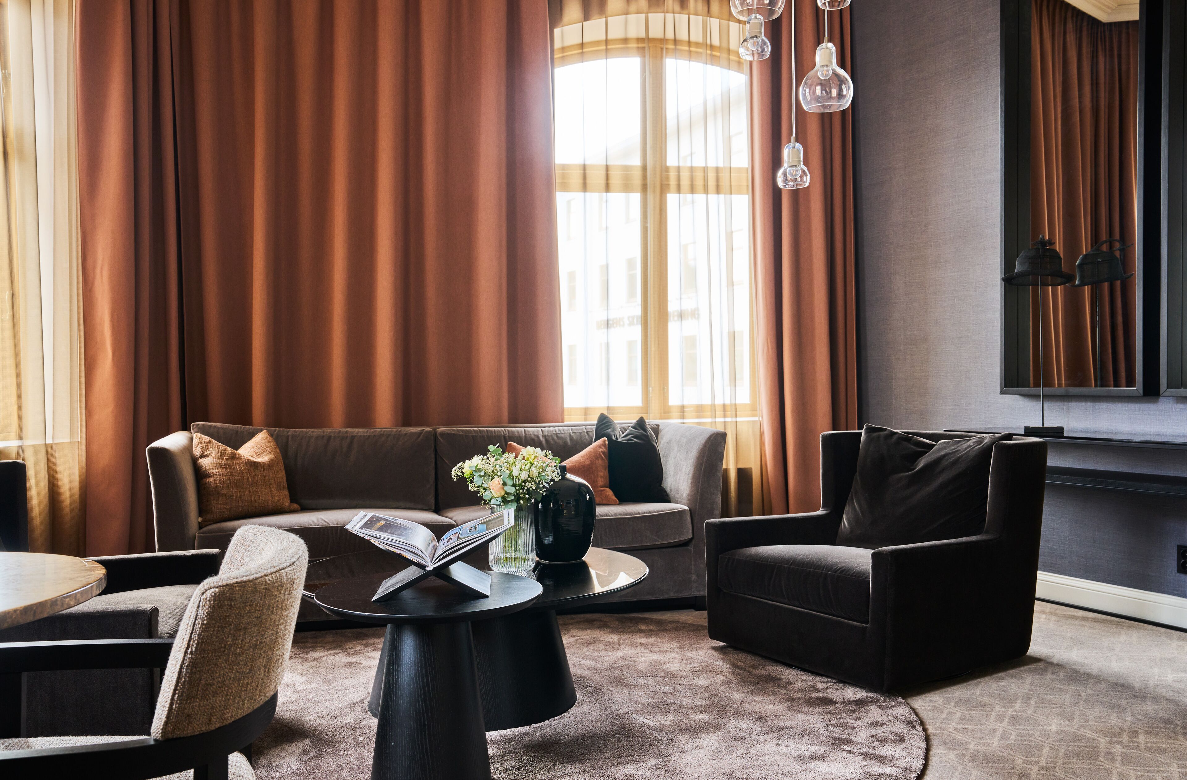 Ein modernes Wohnzimmer mit einer Couch, Sesseln, einem Couchtisch und einem Kamin.