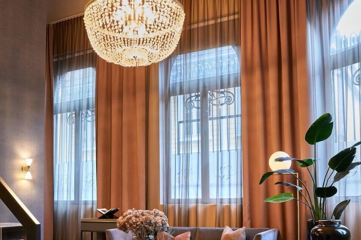 A modern living room with a large chandelier, a sofa set, a coffee table, and a potted plant.