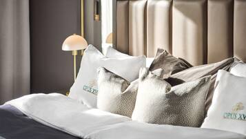 A neatly made bed with white bedding and decorative pillows, a bedside lamp, and a headboard with vertical slats.