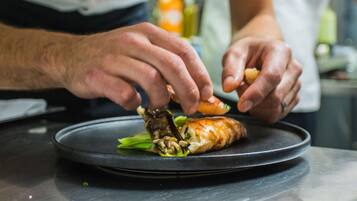 A person preparing food on a black plate with a focus on hands and a pastry.