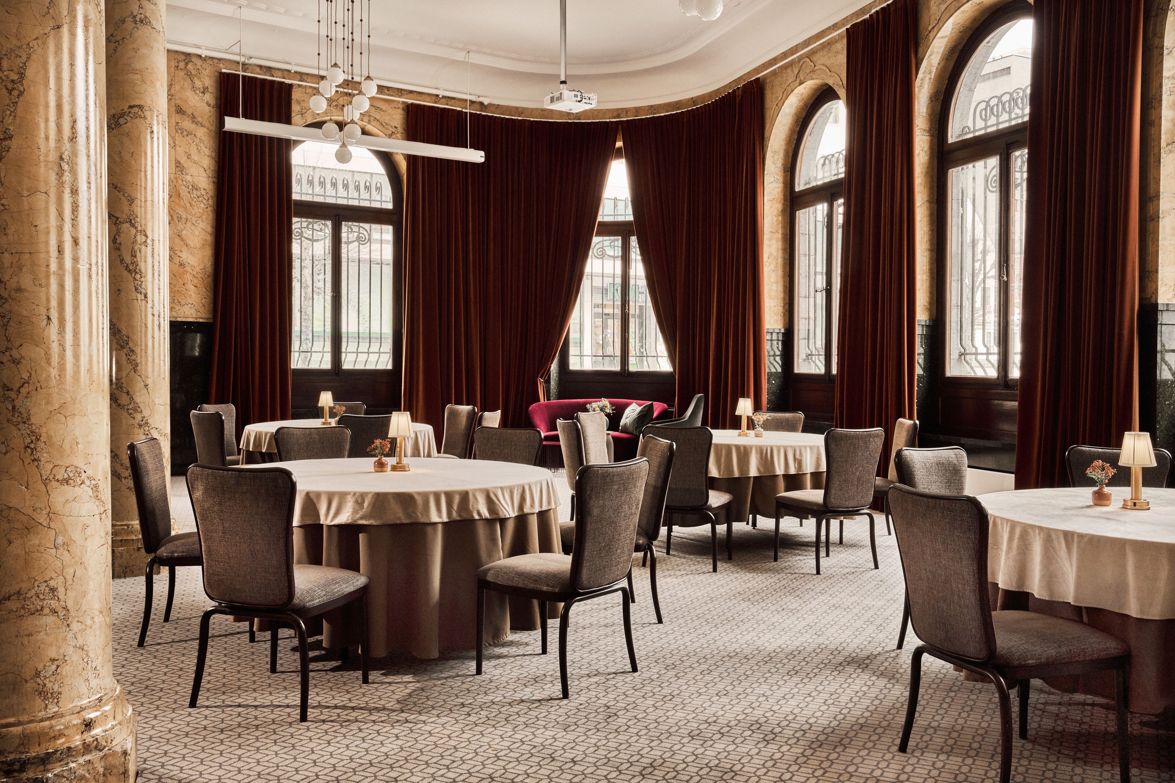 A formal dining room with round tables, chairs, and a chandelier.