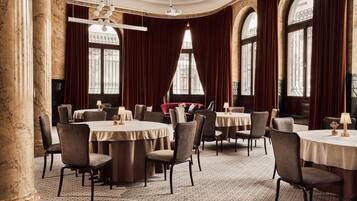 A formal dining room with round tables, chairs, and a chandelier.