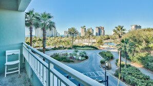 A balcony with a view of a landscaped area, palm trees, and high-rise buildings in the background. - Sandestin Luau Studio, Steps to Beach - Family/Golf, Beach Gear/TRAM/WiFi (Miramar Beach)