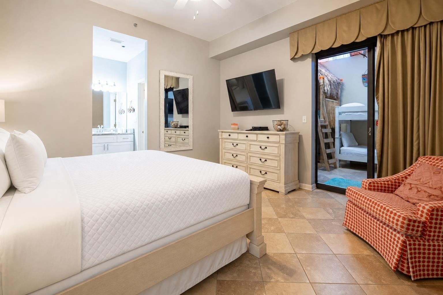 A bedroom with a large bed, a TV, a dresser, and a chair.