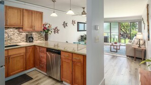 Une cuisine moderne avec des meubles en bois, des appareils électroménagers en acier inoxydable et des luminaires suspendus.