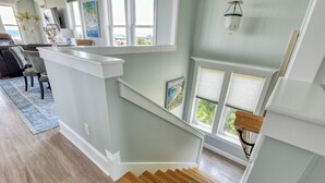 Un escalier avec des marches en bois menant à un palier doté d’une rambarde blanche.