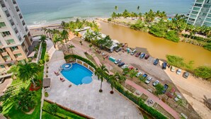 A hotel with a swimming pool, beach, and a river. - Pools, Gym & Restaurant | Beachfront 1BR (Puerto Vallarta)