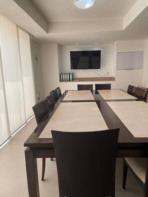 A conference room with a long table, chairs, a flat-screen TV, and a whiteboard. - Pools, Gym & Restaurant | Beachfront 1BR (Puerto Vallarta)