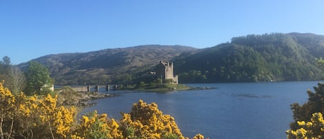 A castle on a lake surrounded by hills.
