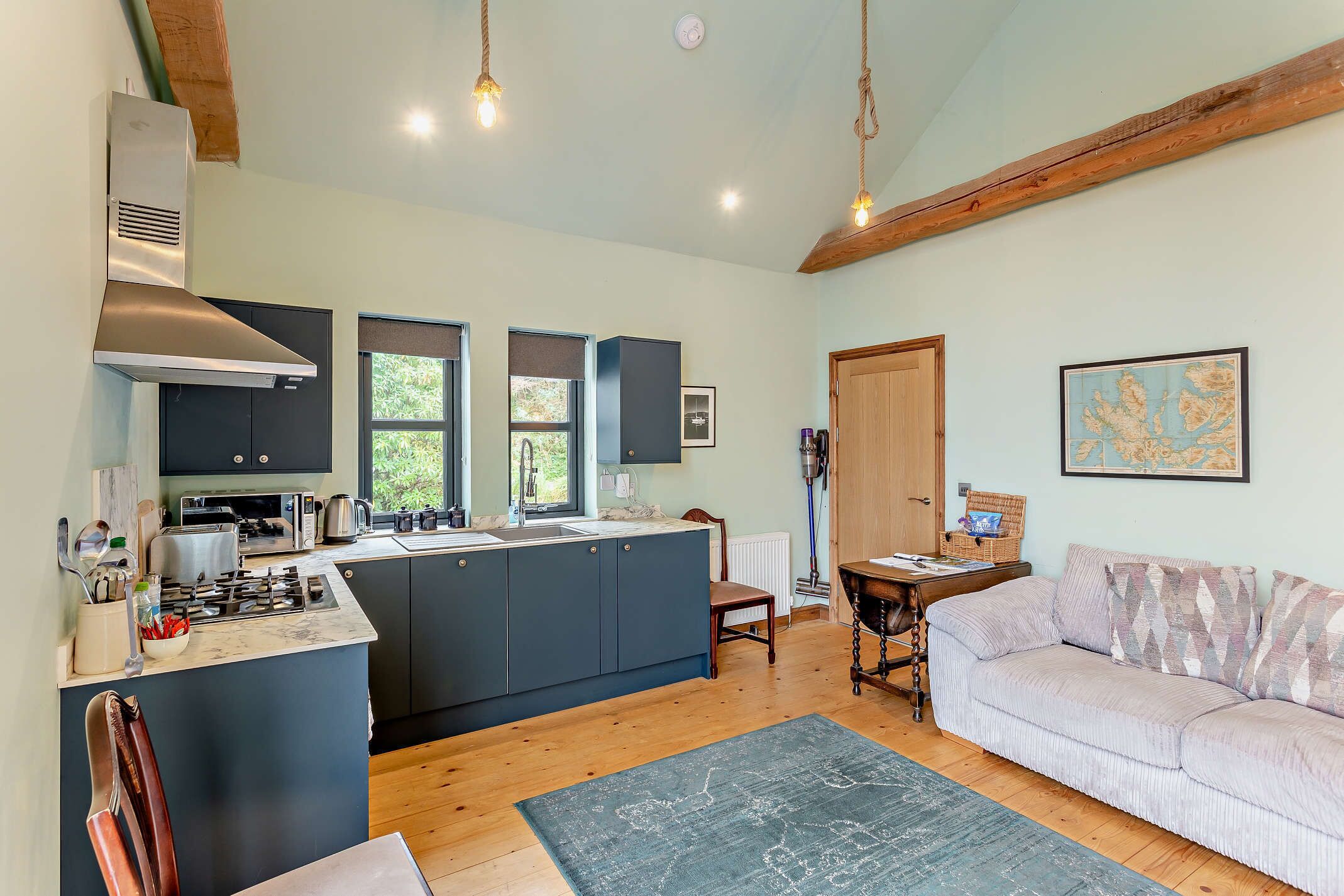 A modern kitchen with a central island, wooden beams, and a cozy seating area with a sofa and a table.