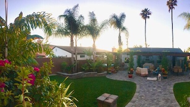 A backyard with a patio, palm trees, and a house in the background. - Roomy, Quaint, Studio Loft w/ Bay View - Central SD Location  (San Diego)