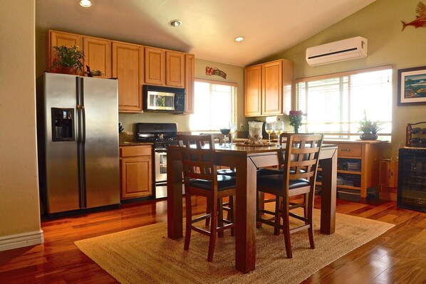 A kitchen with wooden cabinets, a stainless steel refrigerator, a microwave, and a dining area with a table and chairs.