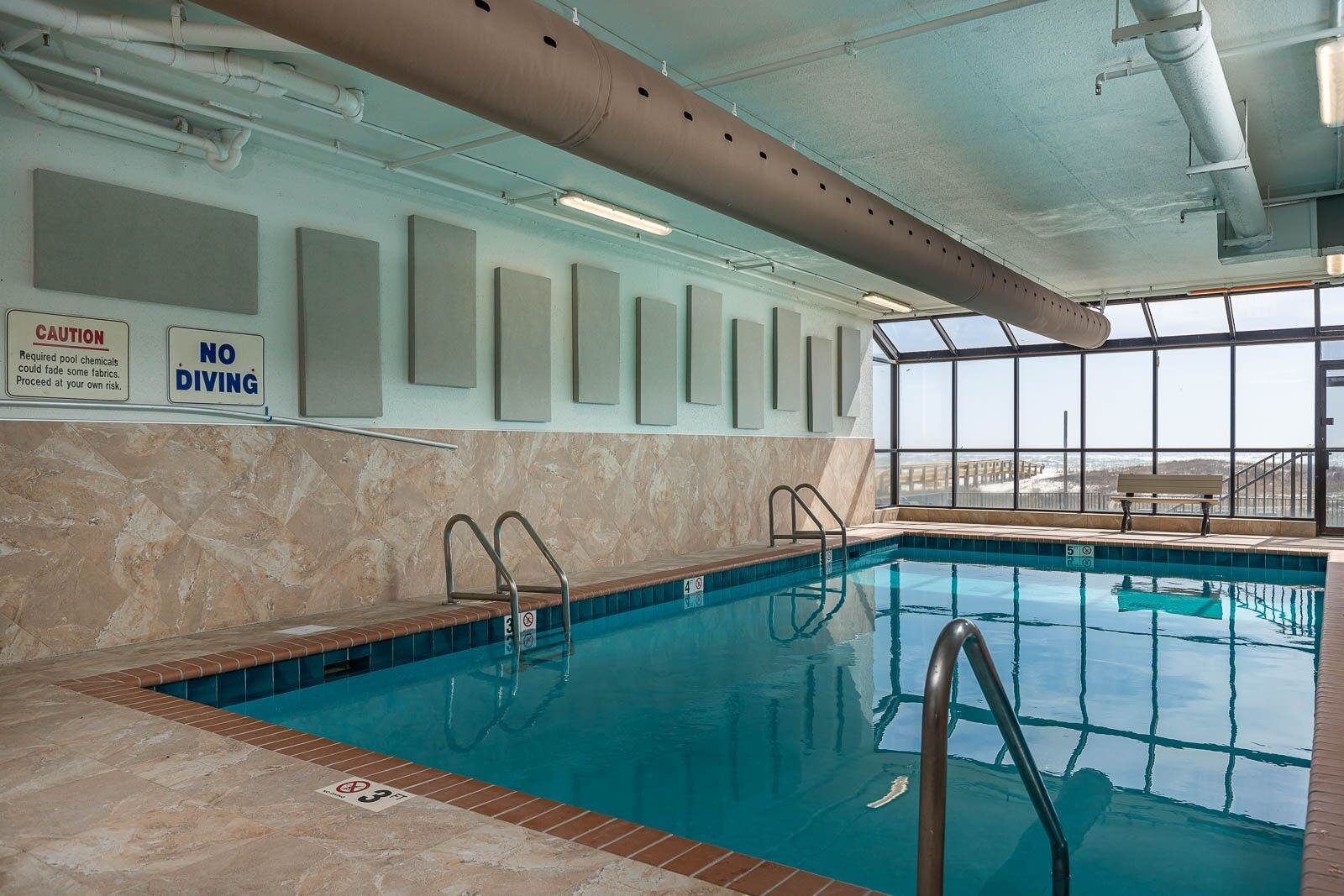 An indoor swimming pool with clear signage, including 'CAUTION' and 'NO DIVING'.