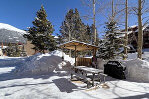 A snow-covered outdoor area with a wooden picnic table and benches, surrounded by snowbanks and trees. - Best Value for Your Money in Ctr Vlg! Gorgeous Sky Chutes view. Free Pkg & WiFi (Copper Mountain)