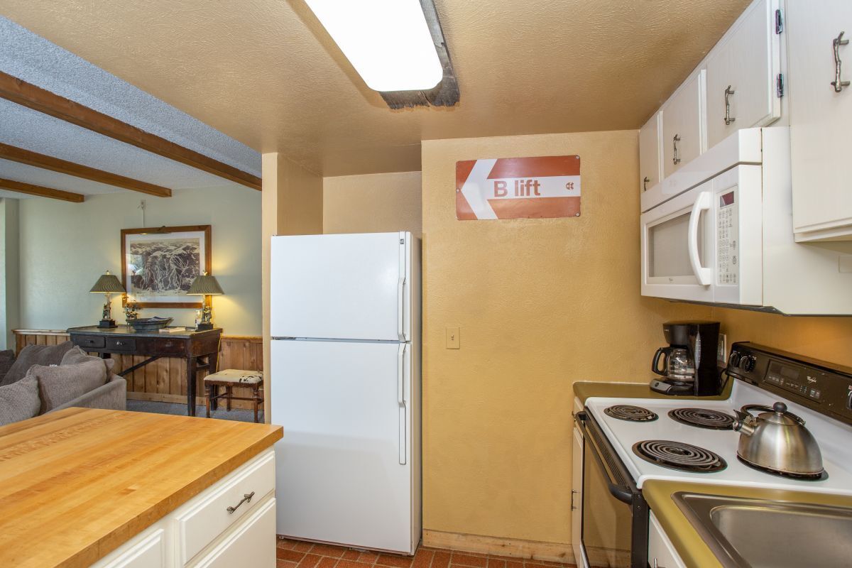 Cocina compacta con refrigerador, estufa, microondas y un letrero de ascensor tipo B.