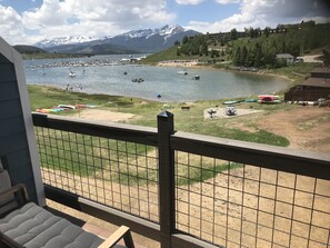 Vista de un lago con barcos, un muelle y montañas al fondo.