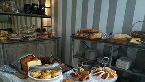 Une table de buffet proposant une variété de produits de boulangerie et de pâtisserie, notamment du pain, des petits pains et des biscuits.