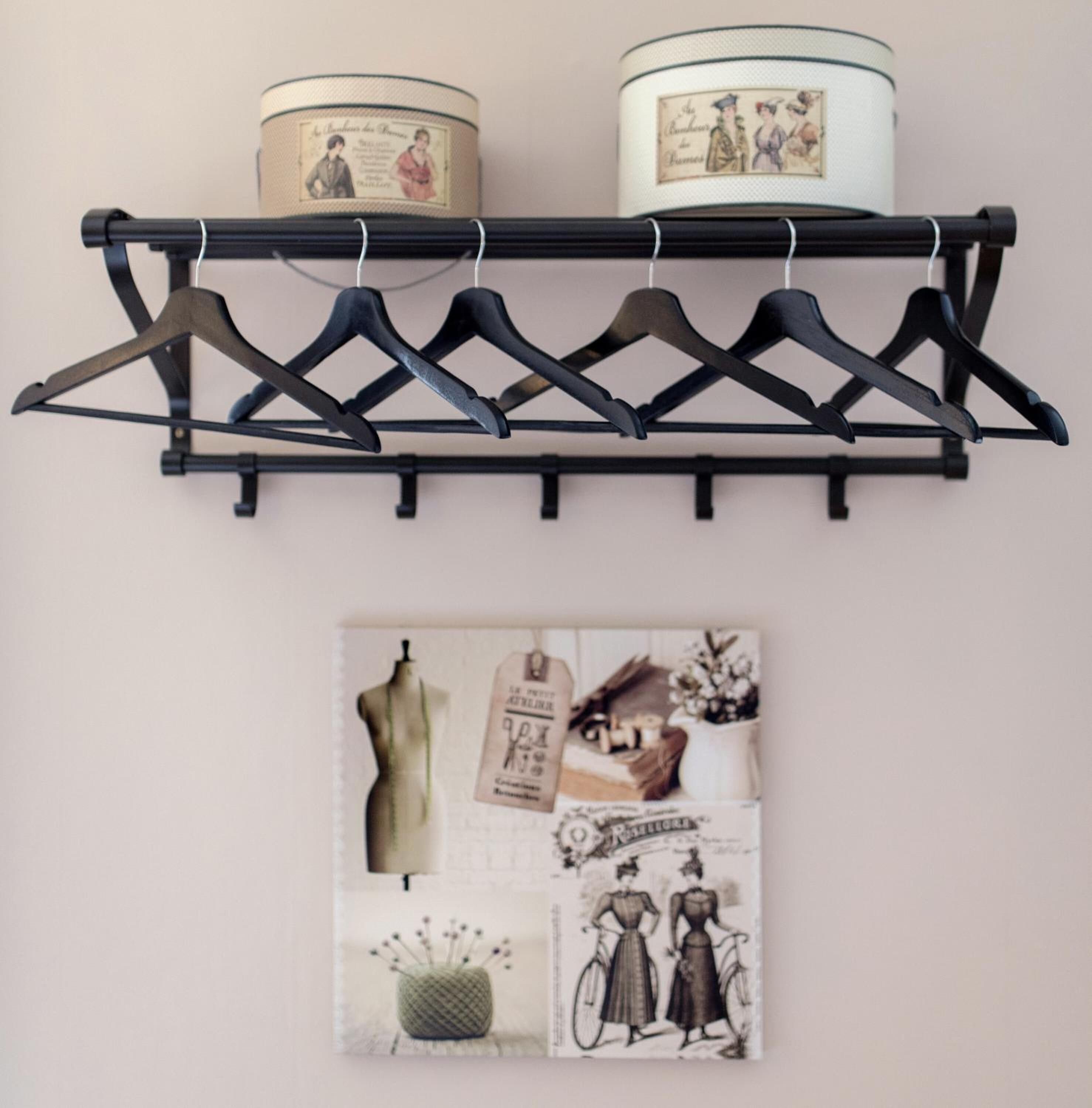 Un perchero negro con seis perchas y dos recipientes decorativos en una pared.