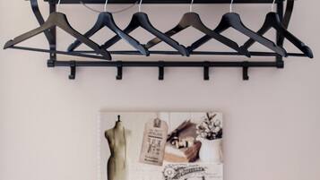 Un perchero negro con seis perchas y dos recipientes decorativos en una pared.