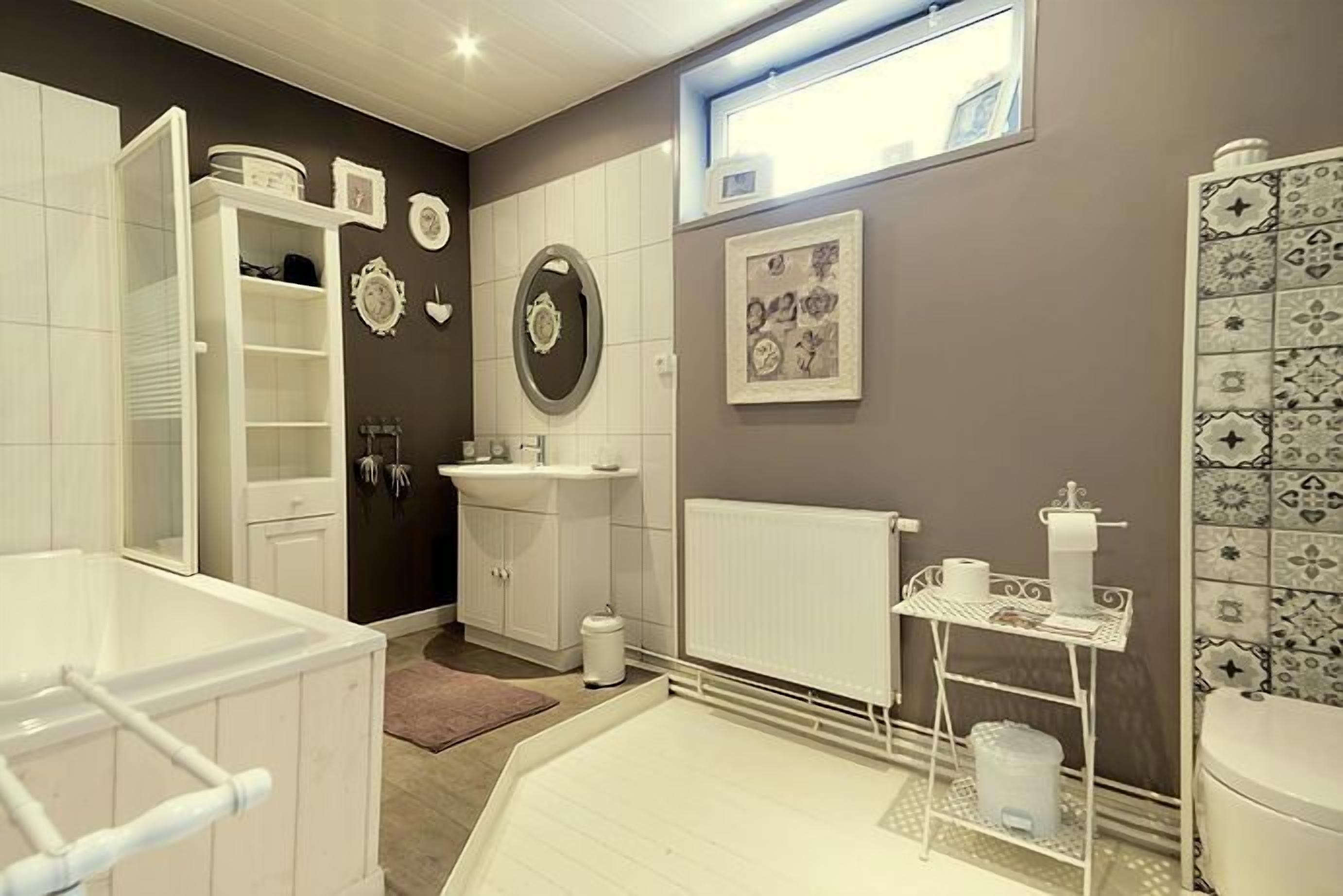 A modern bathroom with a white vanity, a large mirror, and a toilet.