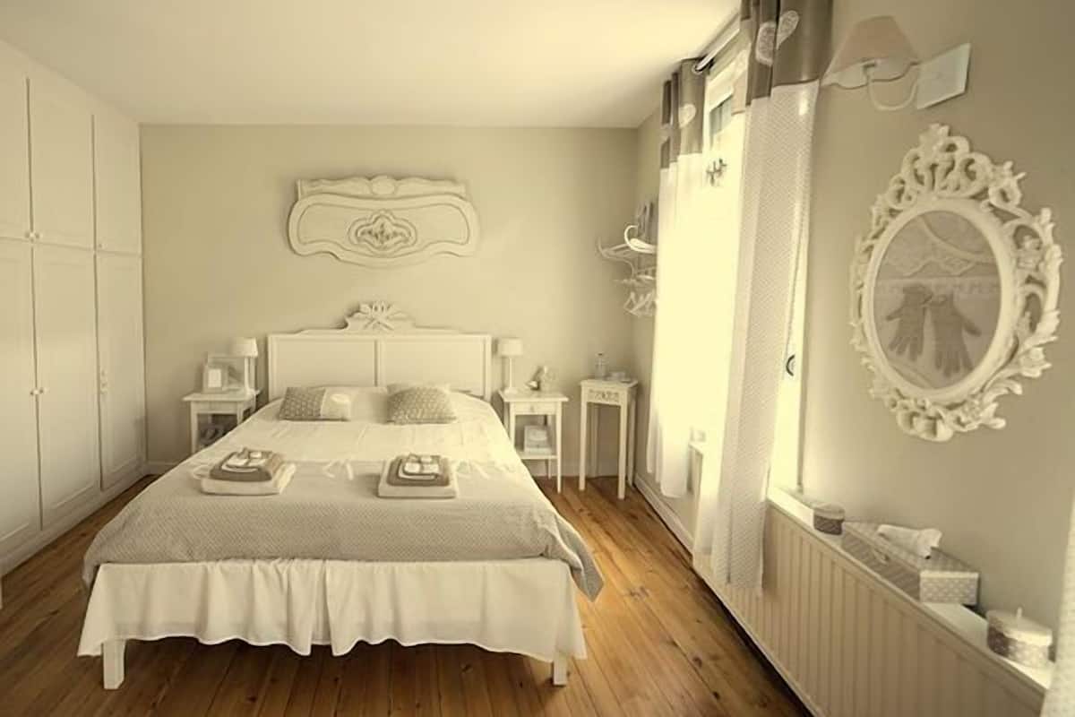 Een slaapkamer met een groot bed, nachtkastjes, een dressoir en een spiegel.
