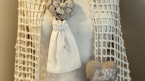Un mannequin vêtu d’une robe blanche, agrémenté d’un châle en crochet et d’éléments décoratifs.
