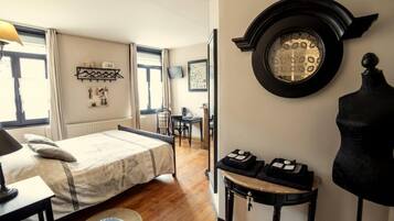 Une chambre à coucher de taille réduite, comprenant un lit, un bureau, une chaise et un miroir rond accroché au mur.