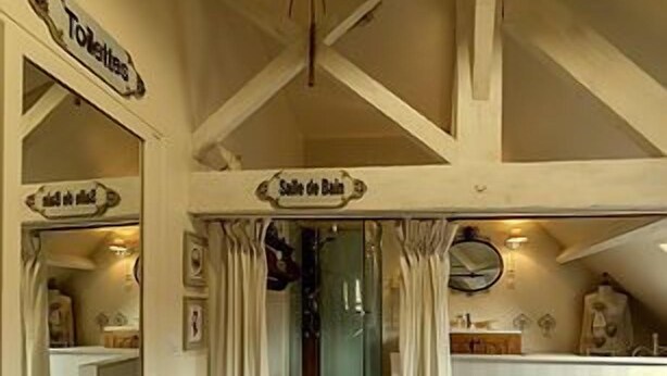 Une pièce avec un plancher en bois, une cabine de douche en verre et un lit doté d’une tête de lit blanche.