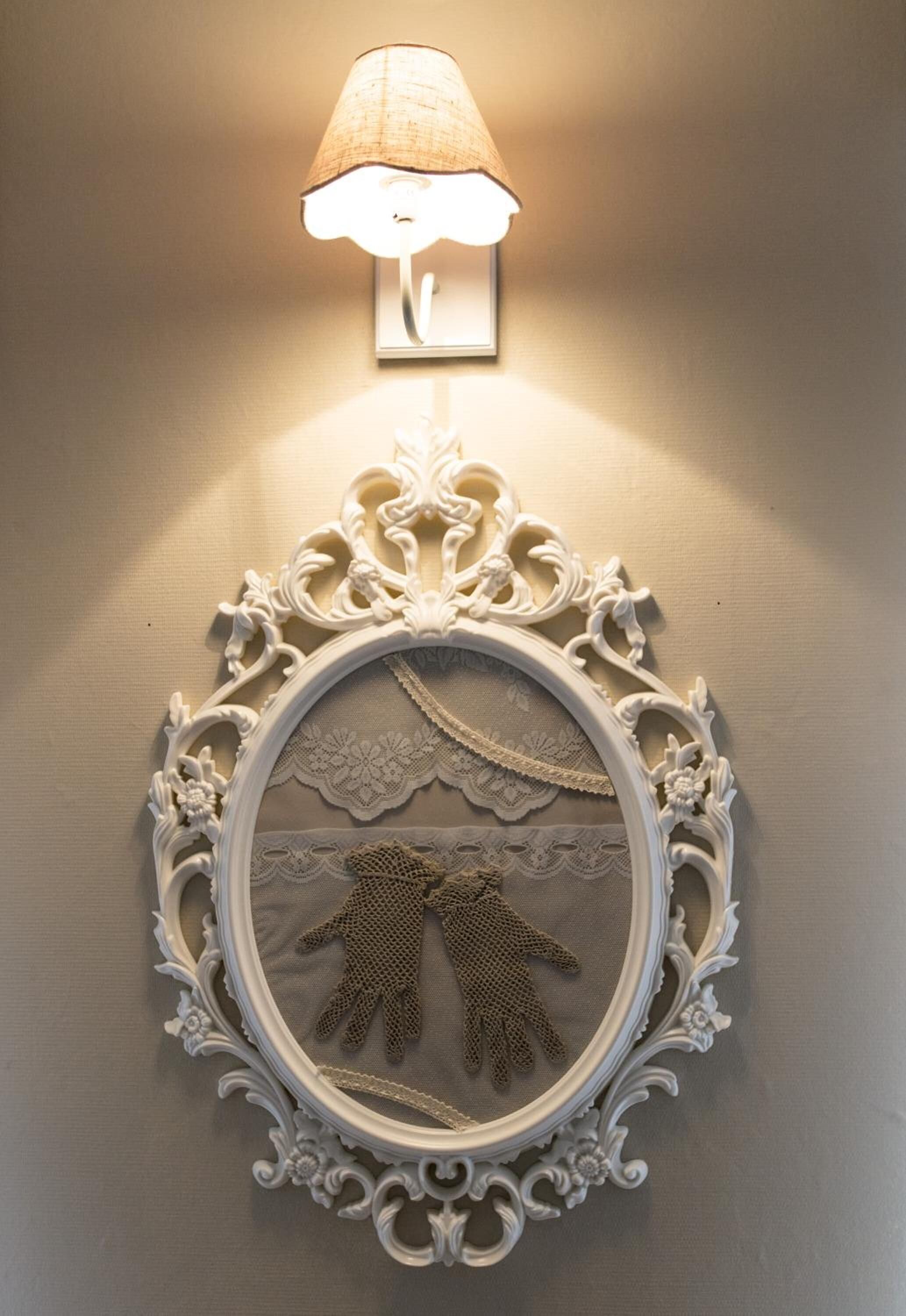 A wall-mounted decorative mirror with an ornate frame and a lamp above it.