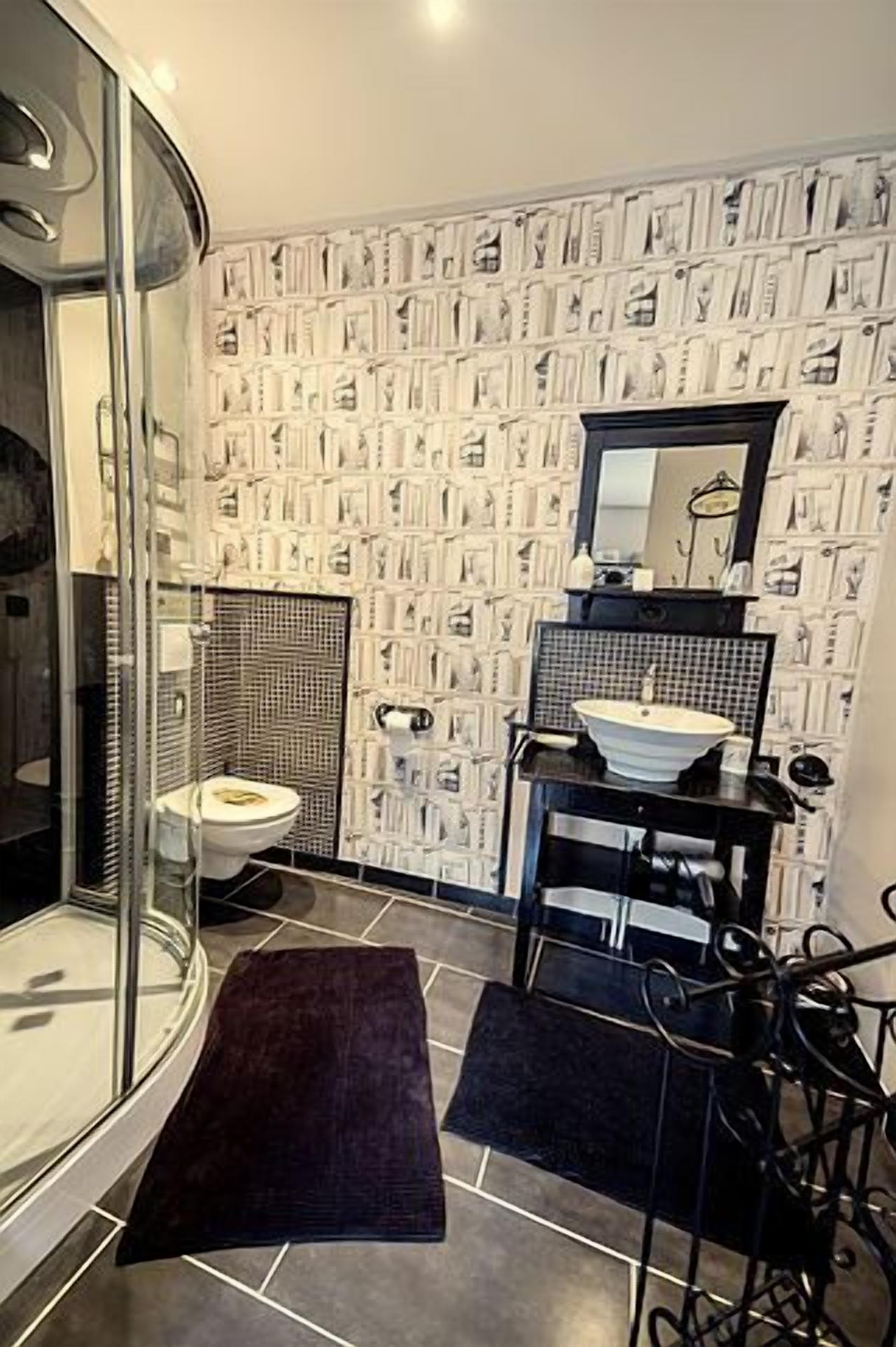 Baño con ducha, inodoro, lavabo y espejo.